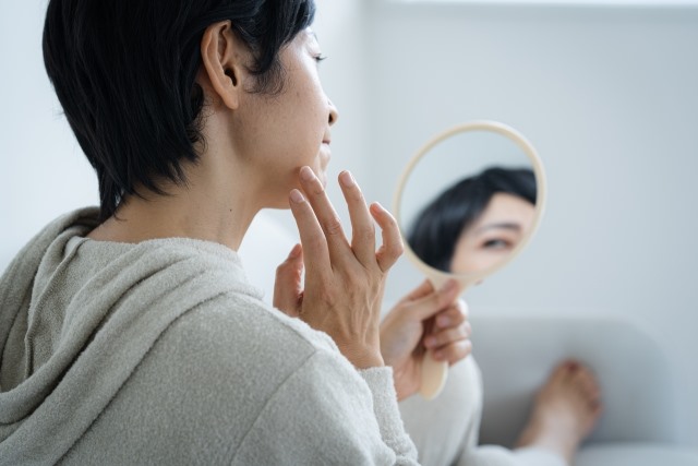 顔のシミに悩む中年女性と美白スキンケア用品のイメージ