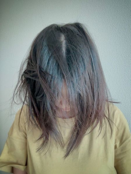 疲れてお風呂に入れずベッドに伏せている人のシルエットと暗い室内