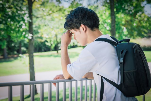 就活で仮面をかぶって本来の自分を隠している学生のイメージ