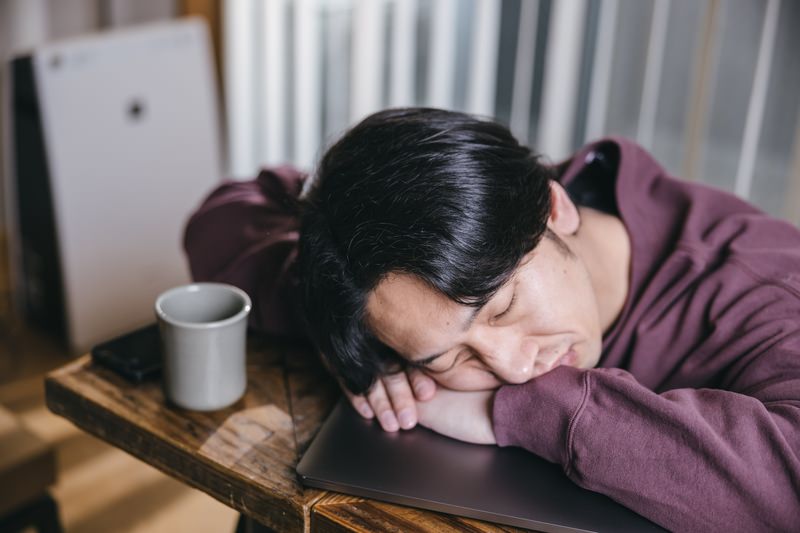 昼食後に眠気と戦うビジネスパーソンと眠気防止に適した健康食材